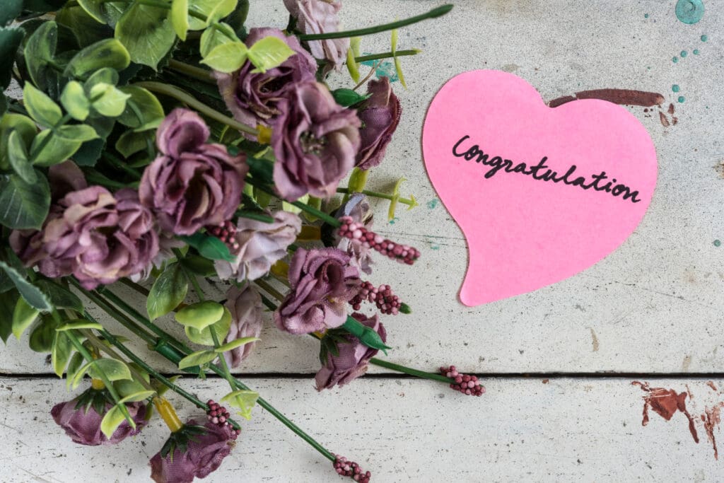 flowers with a heart shaped tag saying congratulations